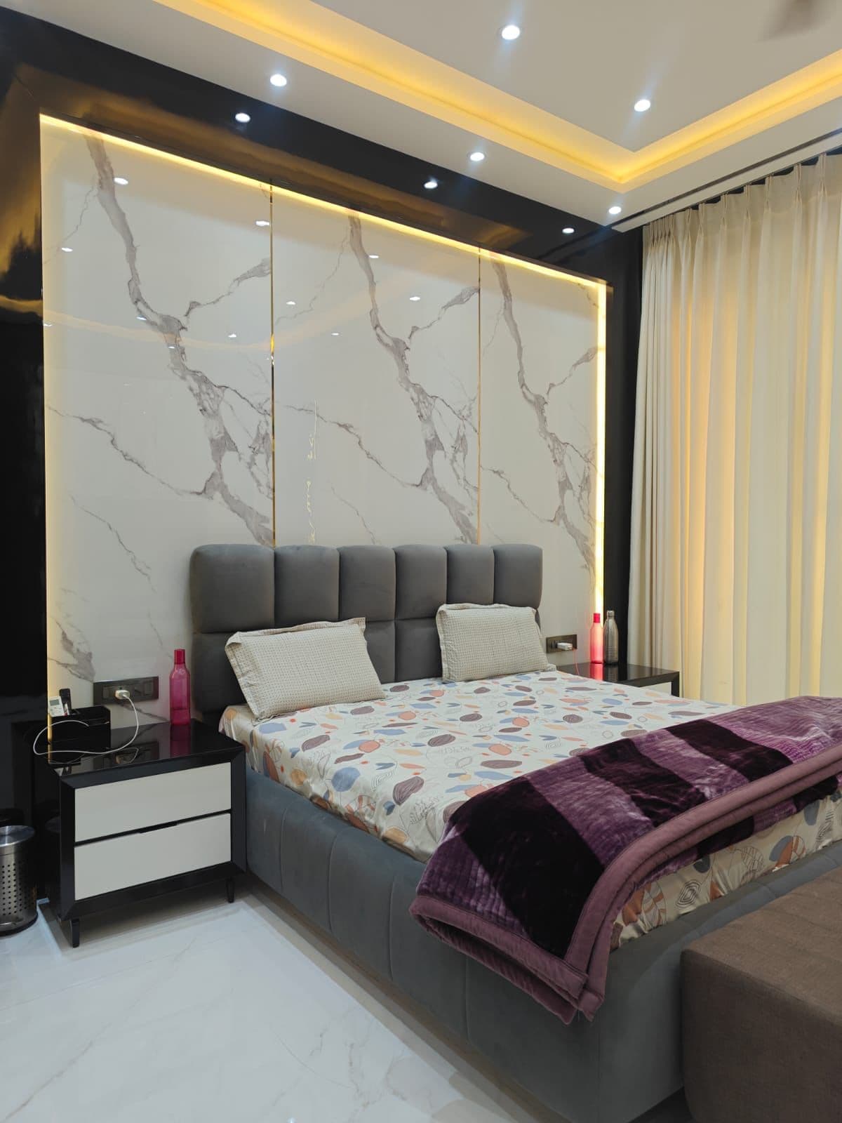 Bedroom — marble feature wall behind a padded velvet headboard
