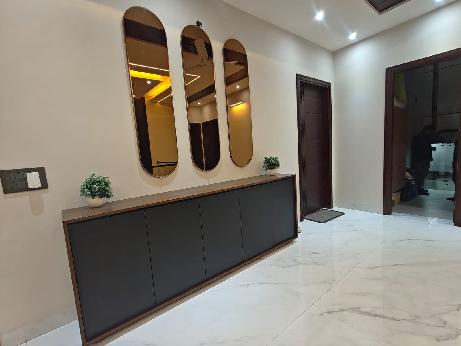 Foyer — three oval mirrors above a walnut-and-black credenza