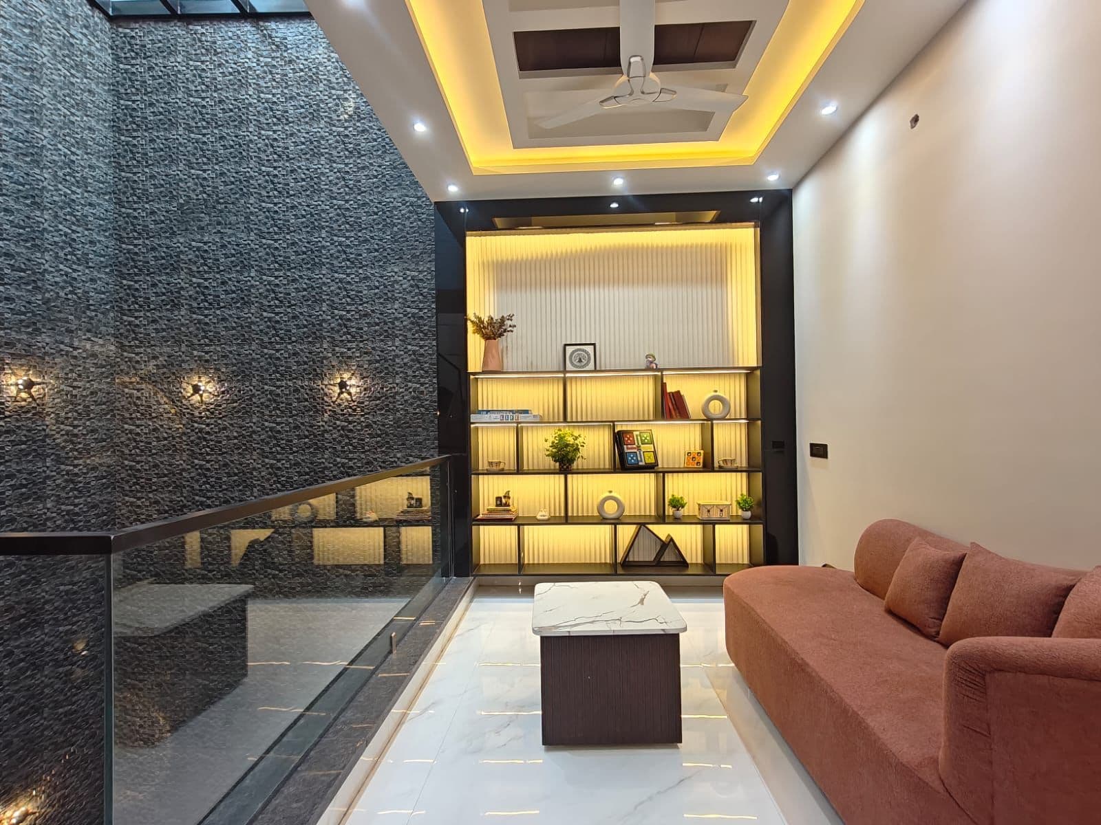 Lounge — terracotta velvet sofa, backlit display niche, rough stone accent wall